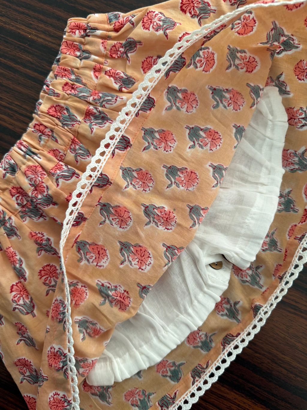 Floral-patterned baby crib with white lining bloomer on a wooden surface