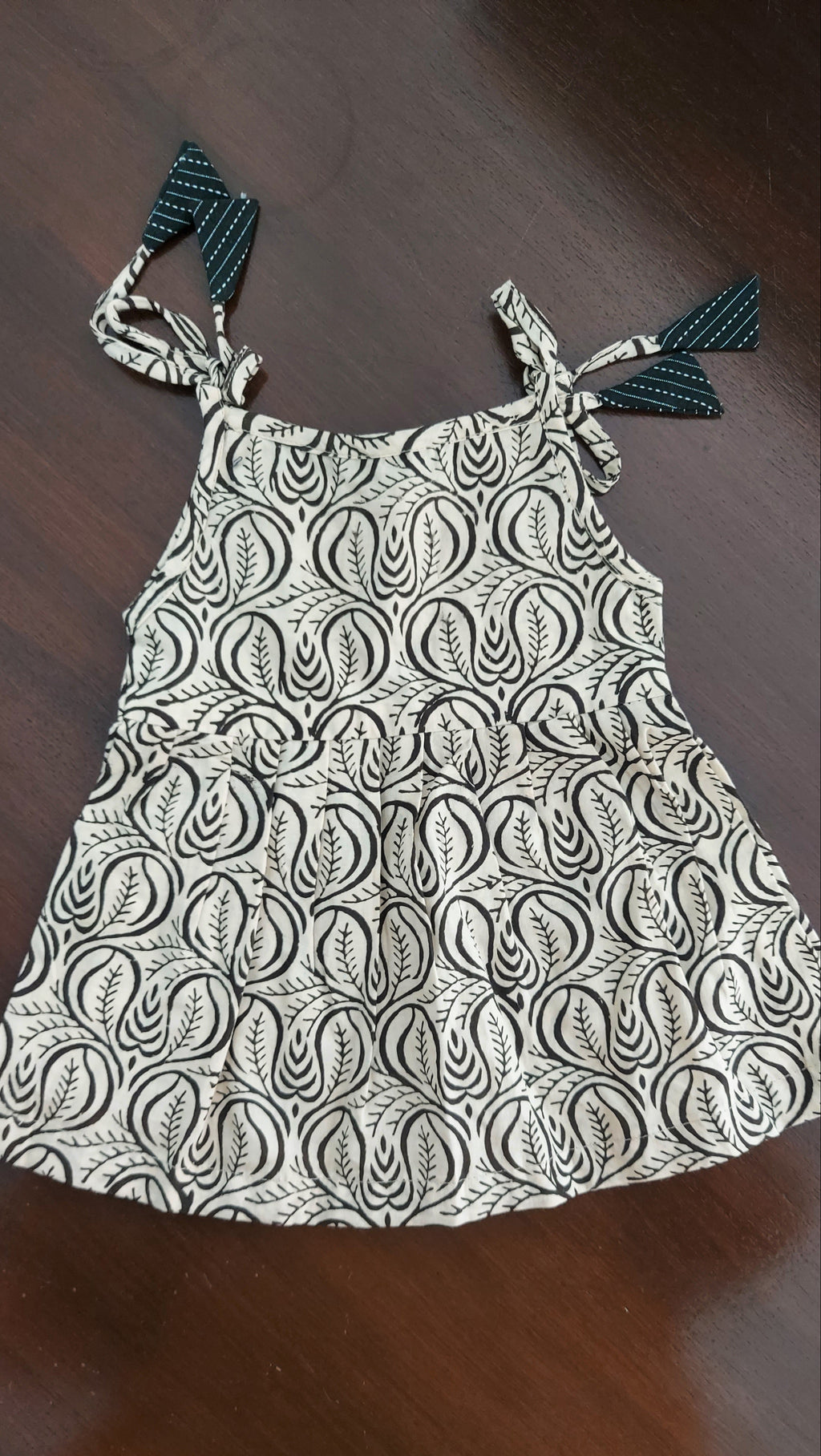 Black and white patterned dress with tassels on a wooden surface