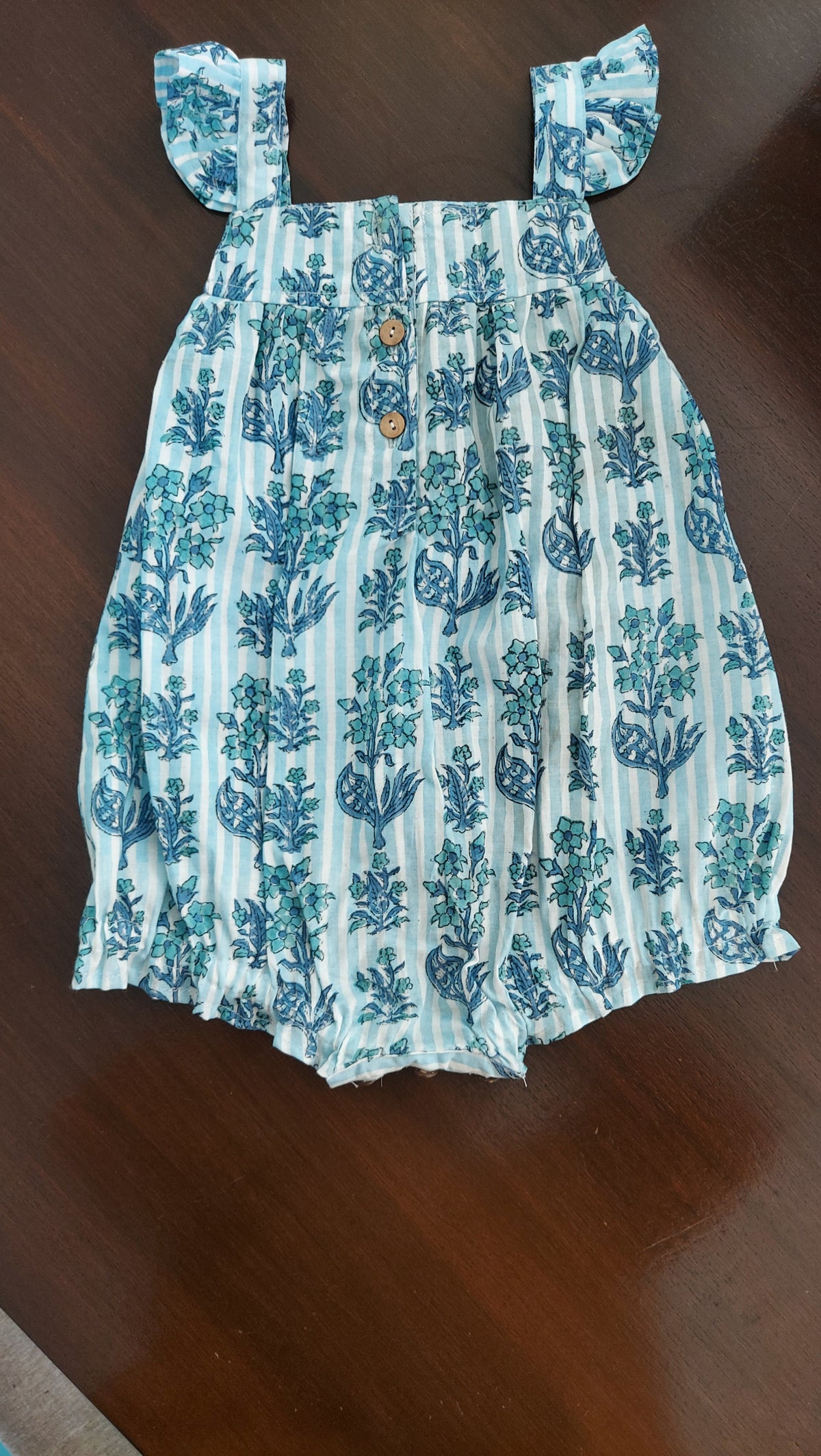 Blue and white patterned dress on a wooden surface with wooden buttons