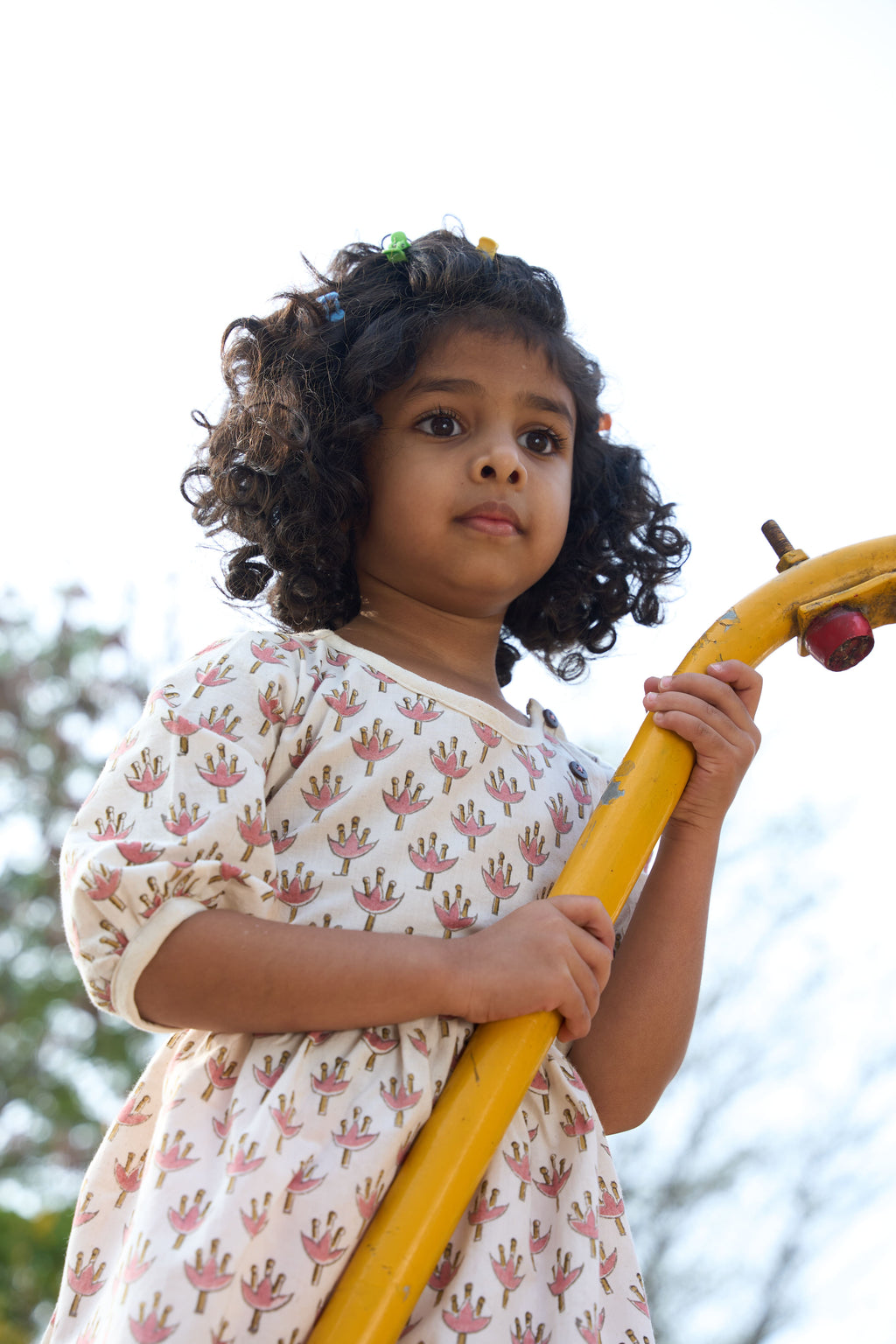 Young girl holding a yellow playground structure with a blurred natural background