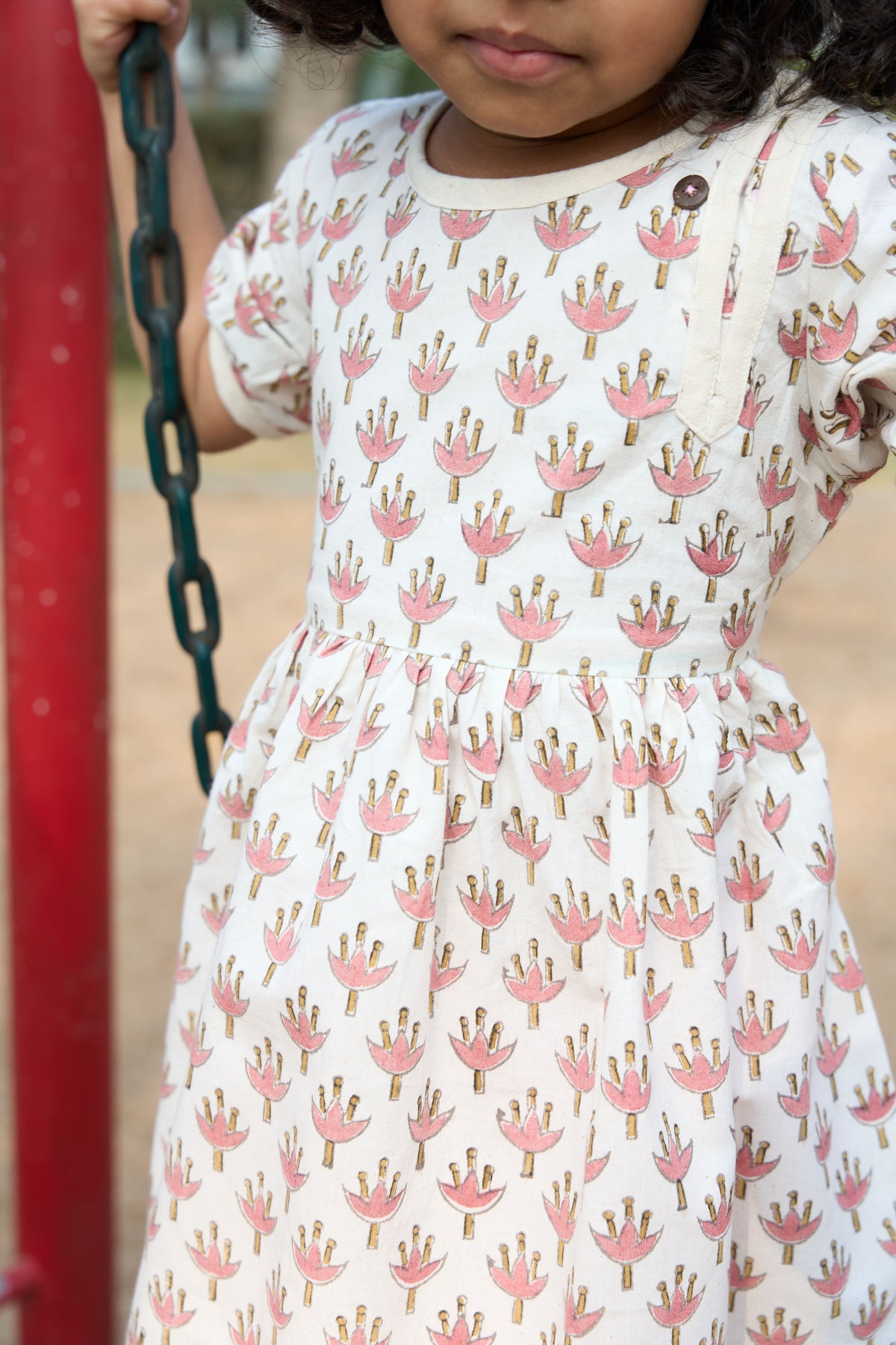 Child wearing a dress with a floral pattern on a playground.