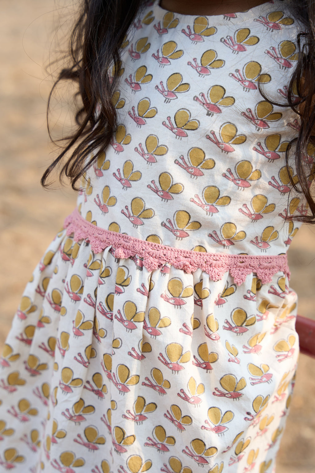 Child wearing a dress with butterfly pattern on a blurred natural background