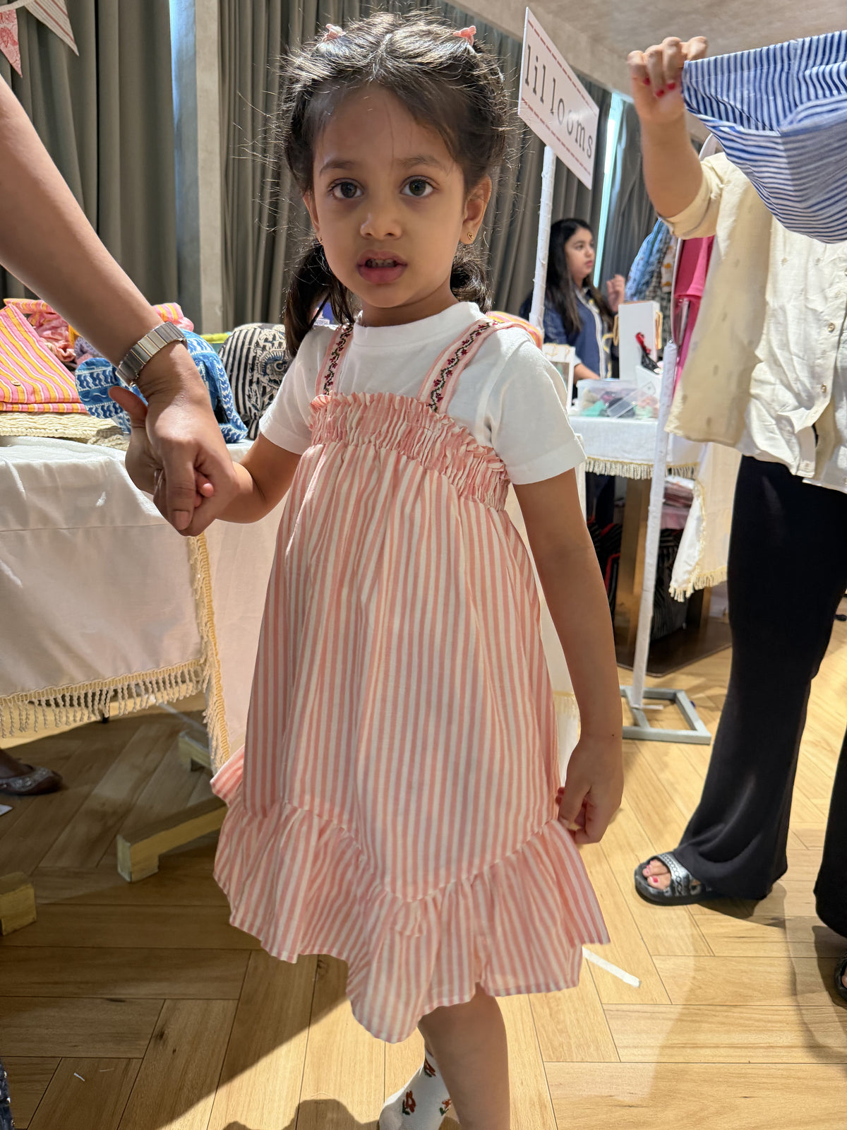 Child wearing a pink and white striped dress in a store setting