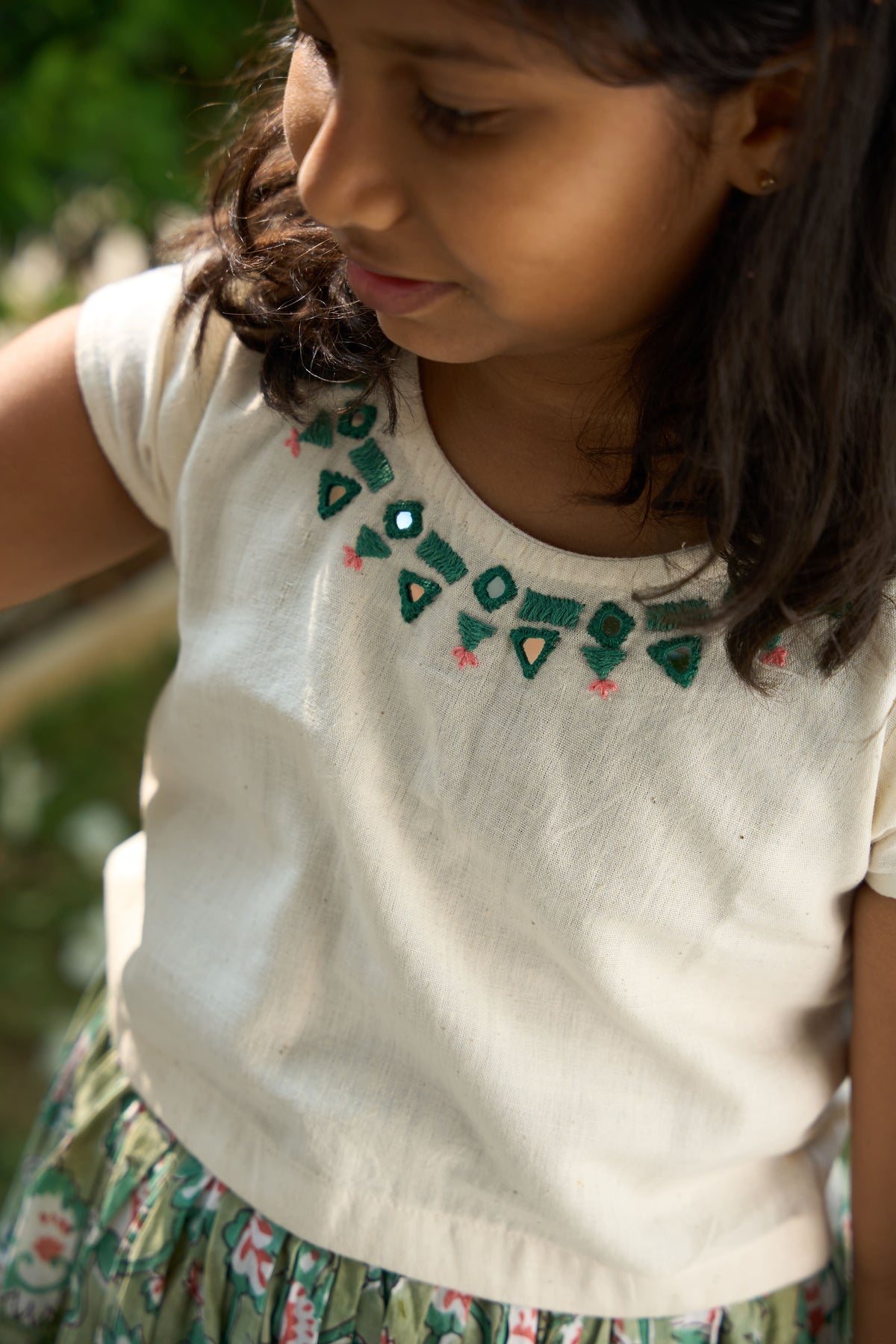 Young girl wearing a white t-shirt with green patterns outdoors