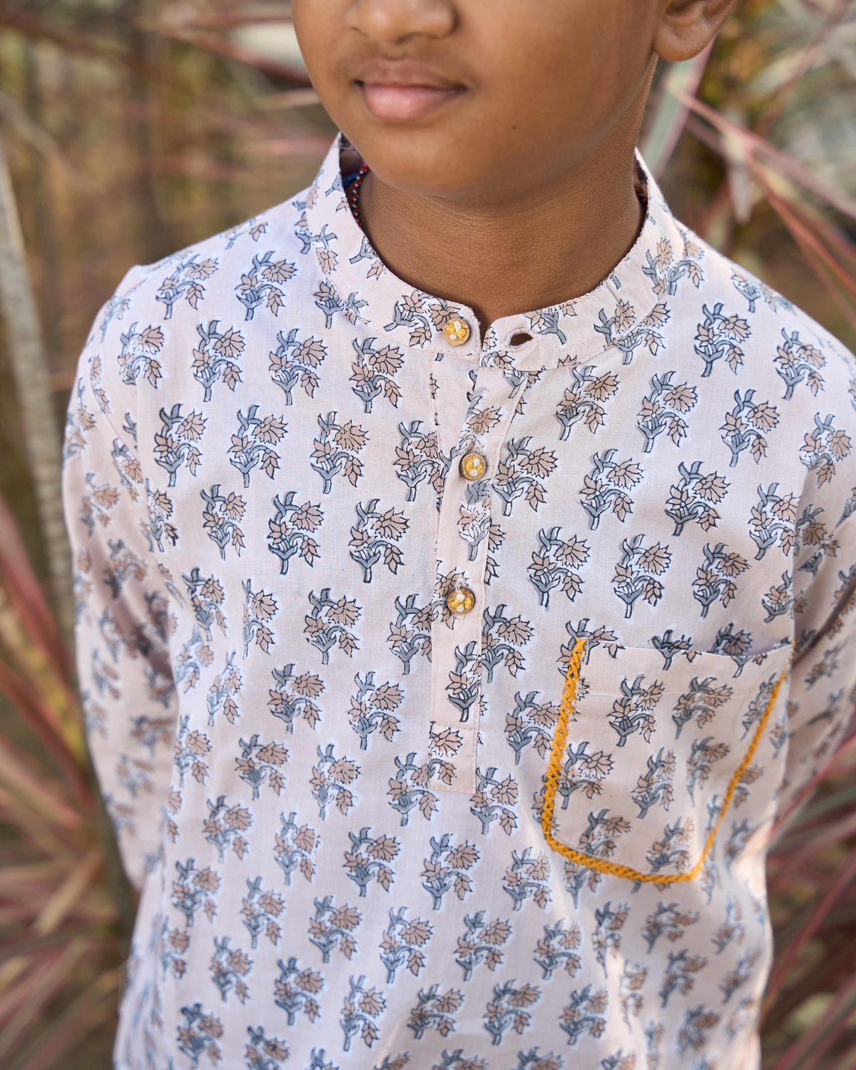 Child wearing a printed kurta with plants in the background