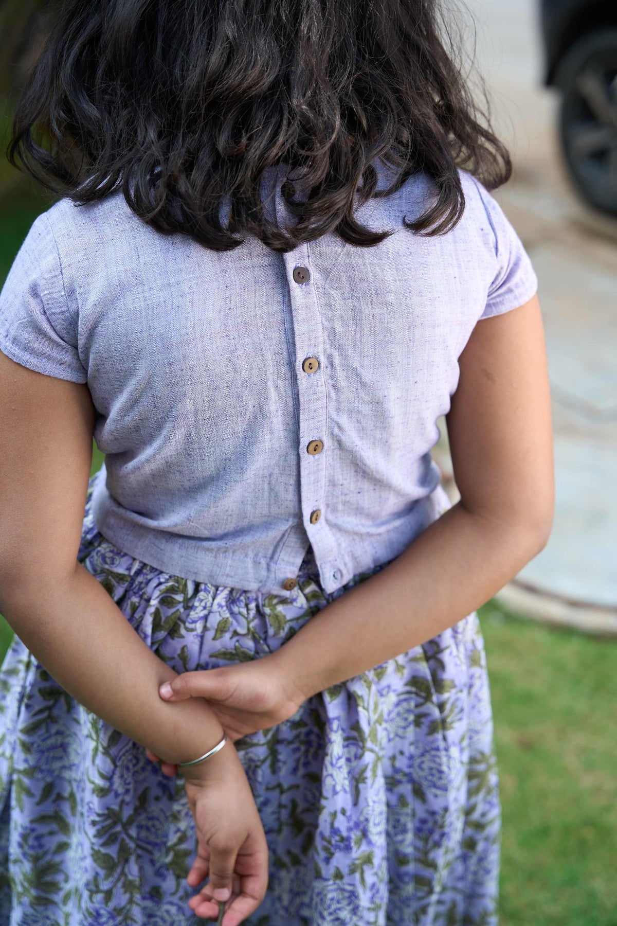 Person wearing a light purple shirt and floral skirt outdoors