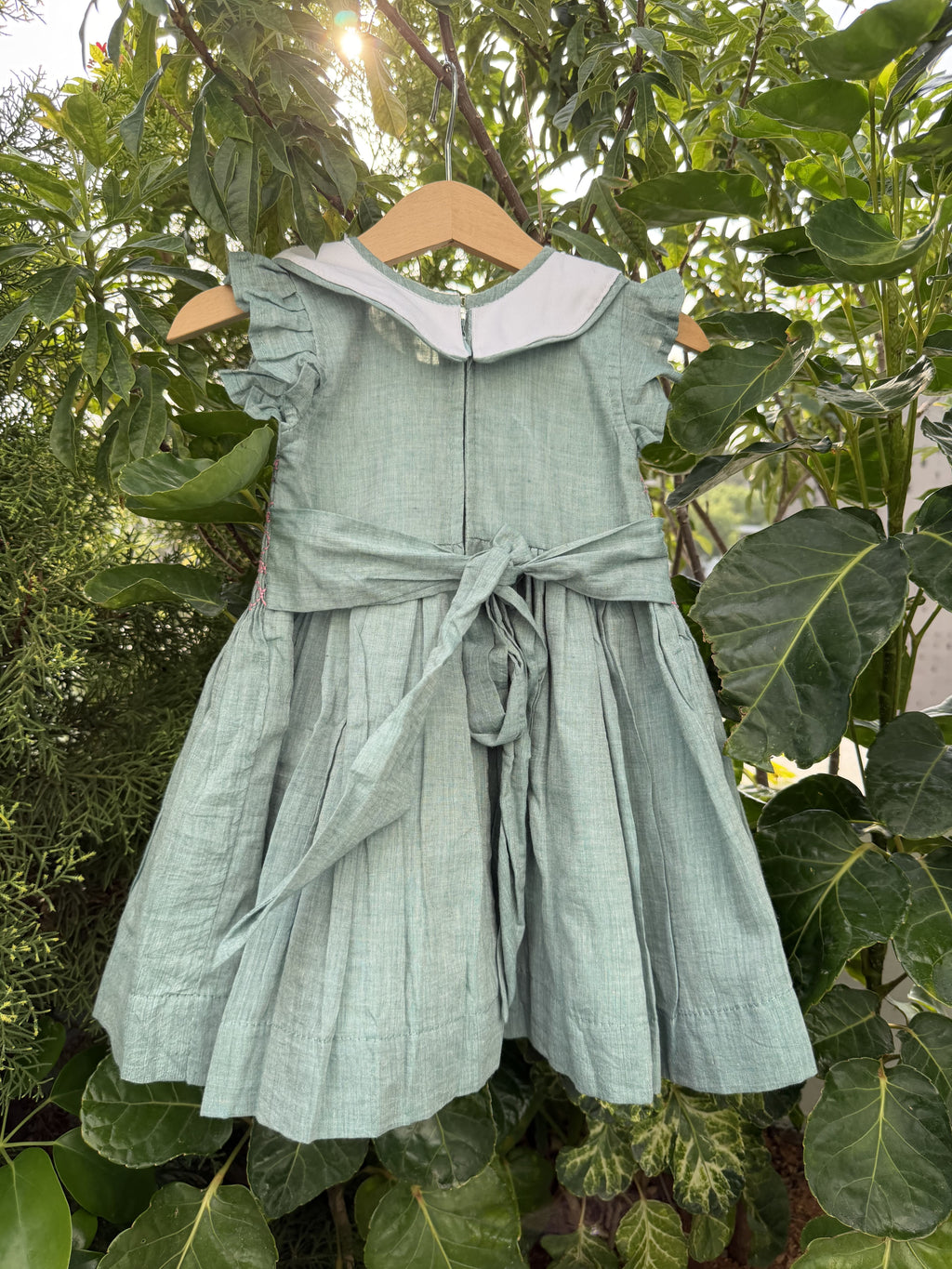 Green dress on a mannequin against a leafy green background