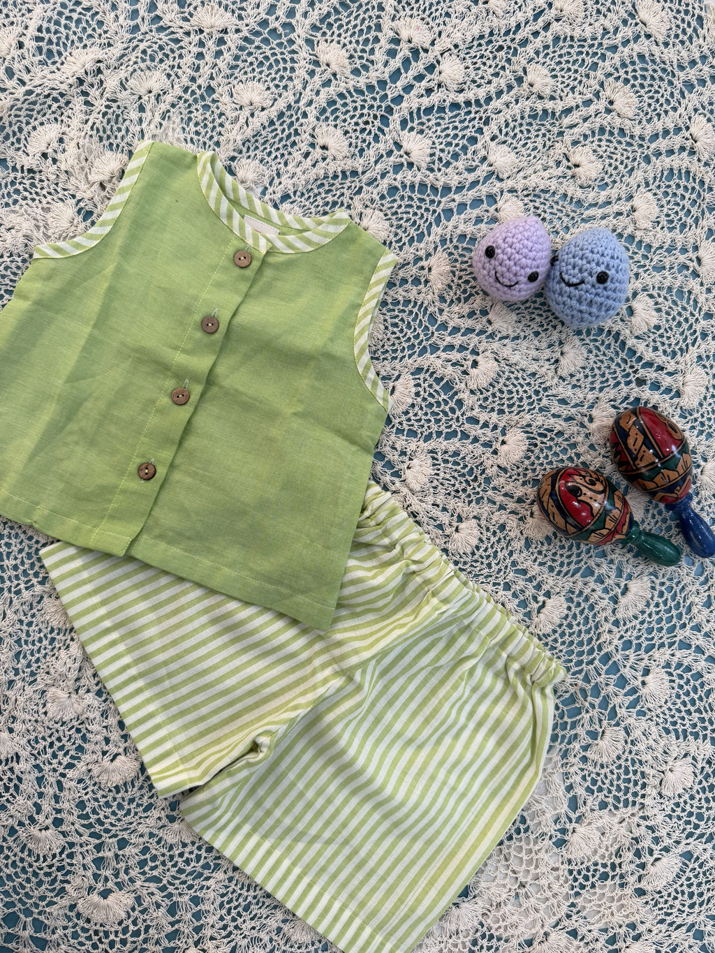 Green baby romper with striped pants on a textured lace tablecloth