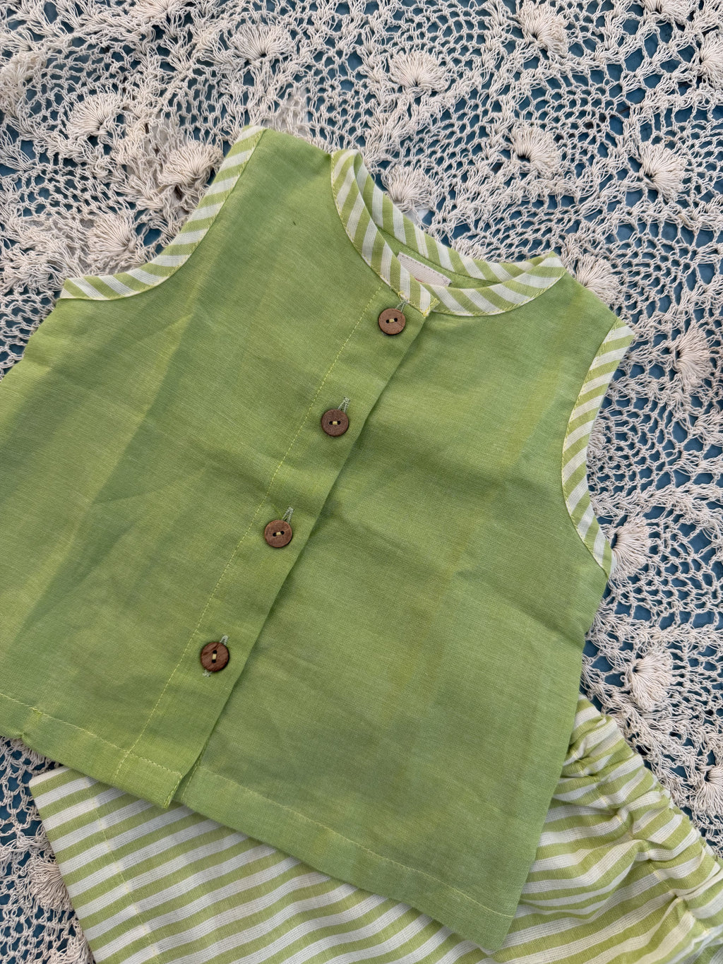 Green fabric with buttons on a lace tablecloth