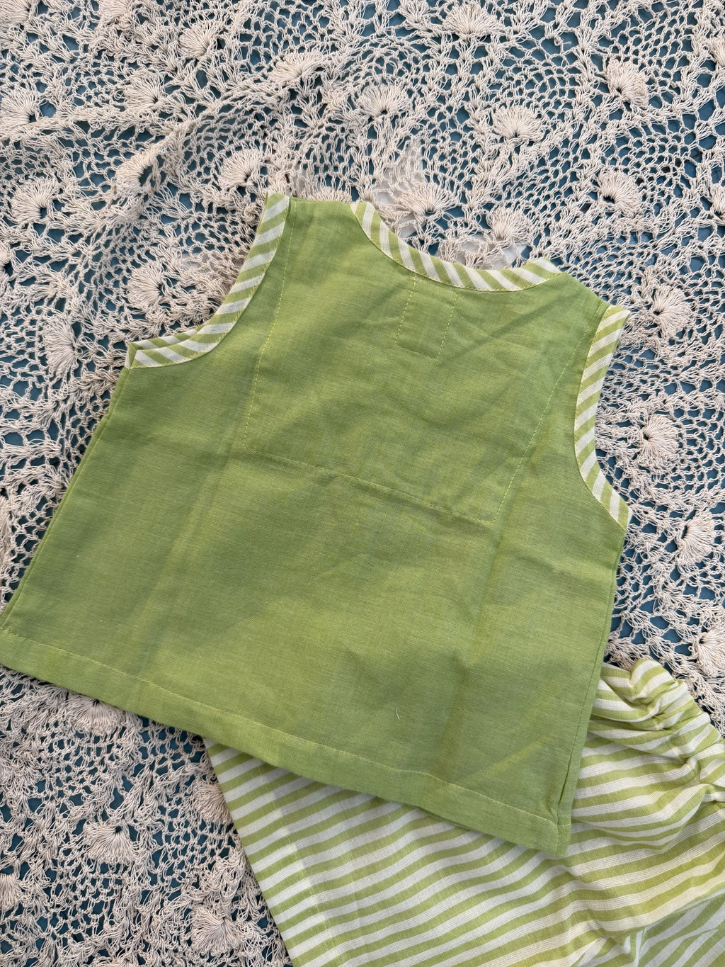 Green fabric with striped trim on a textured surface