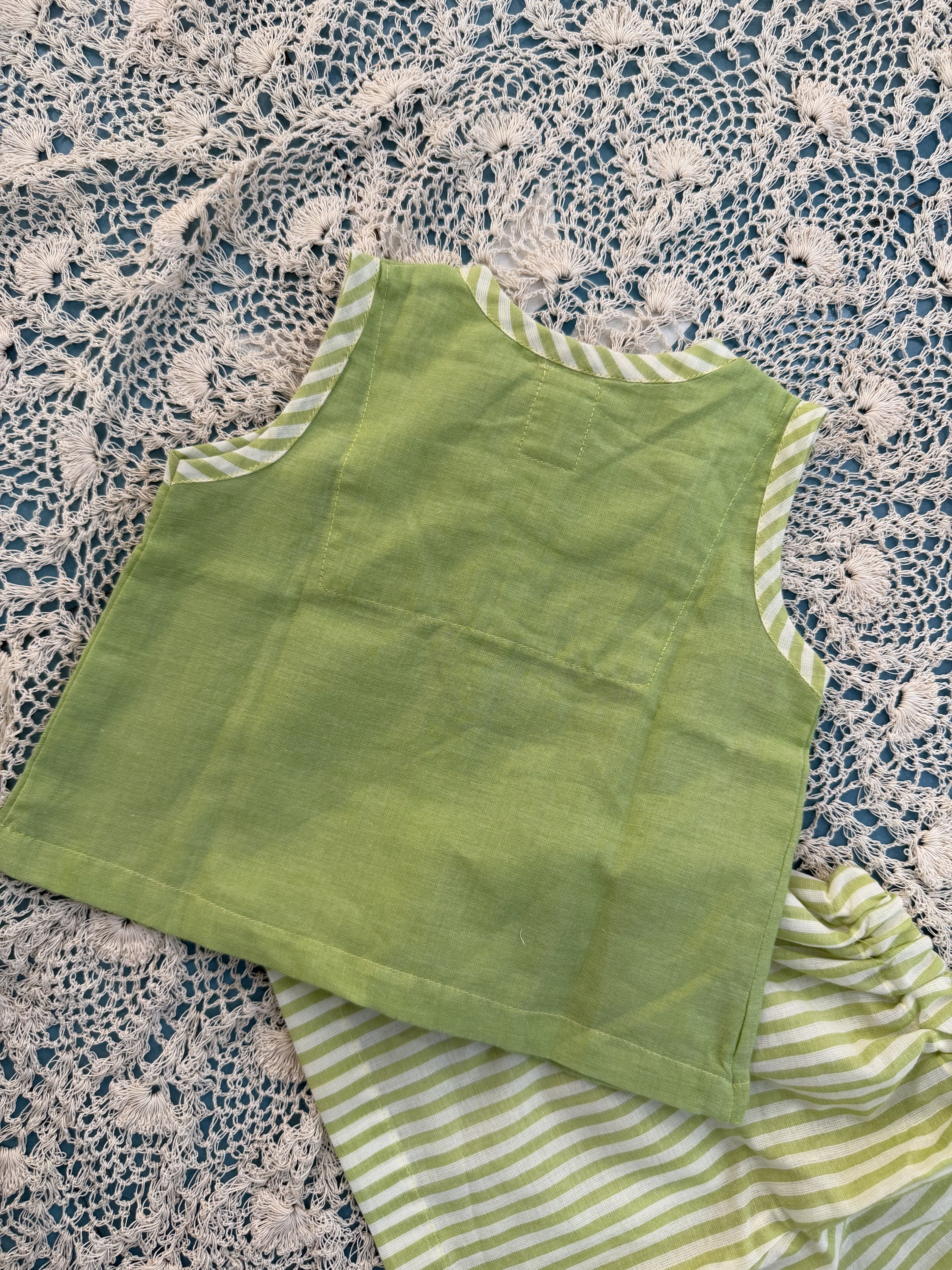 Green fabric with striped trim on a textured surface