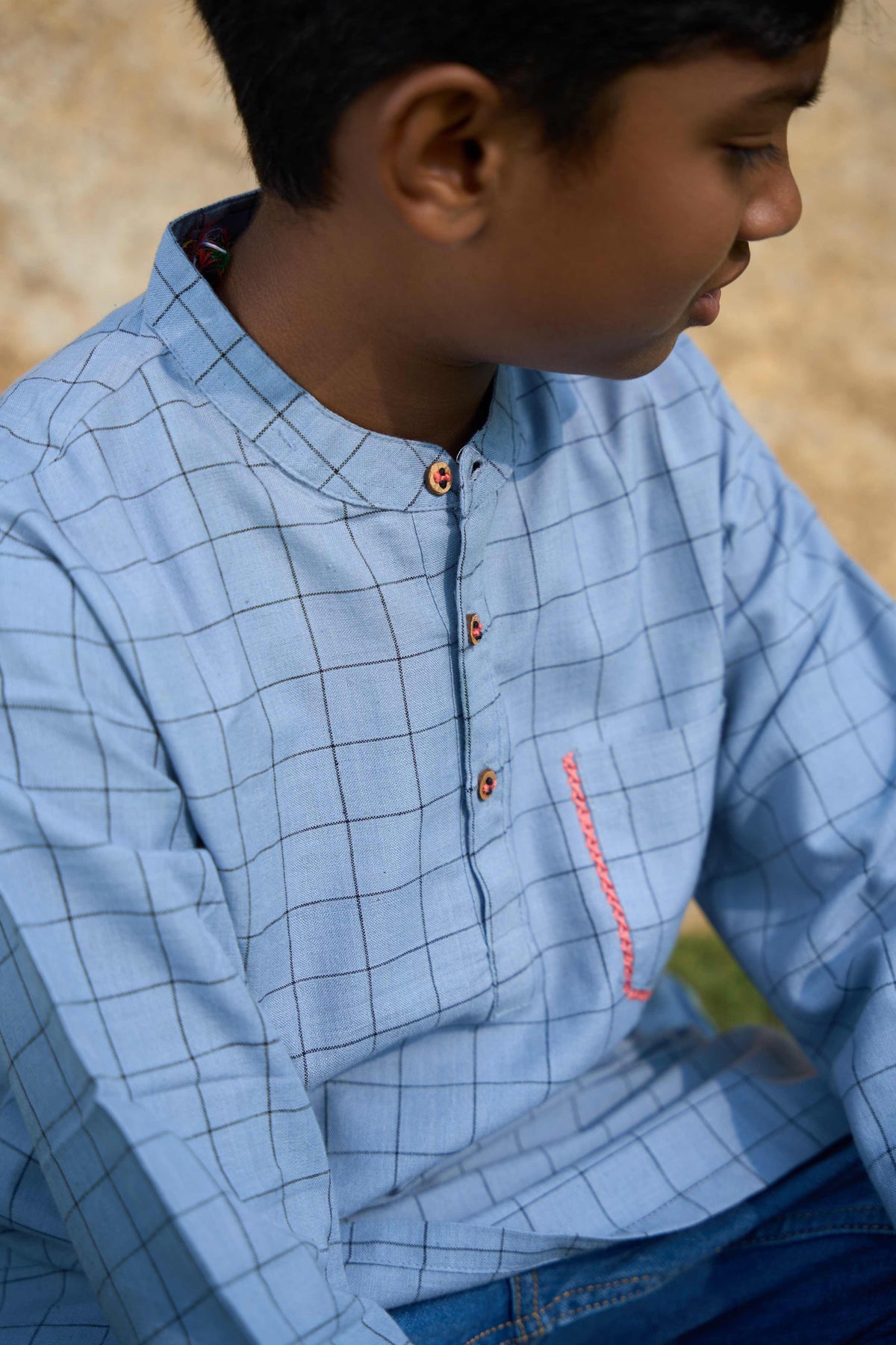 Child wearing a blue checkered shirt with a blurred background