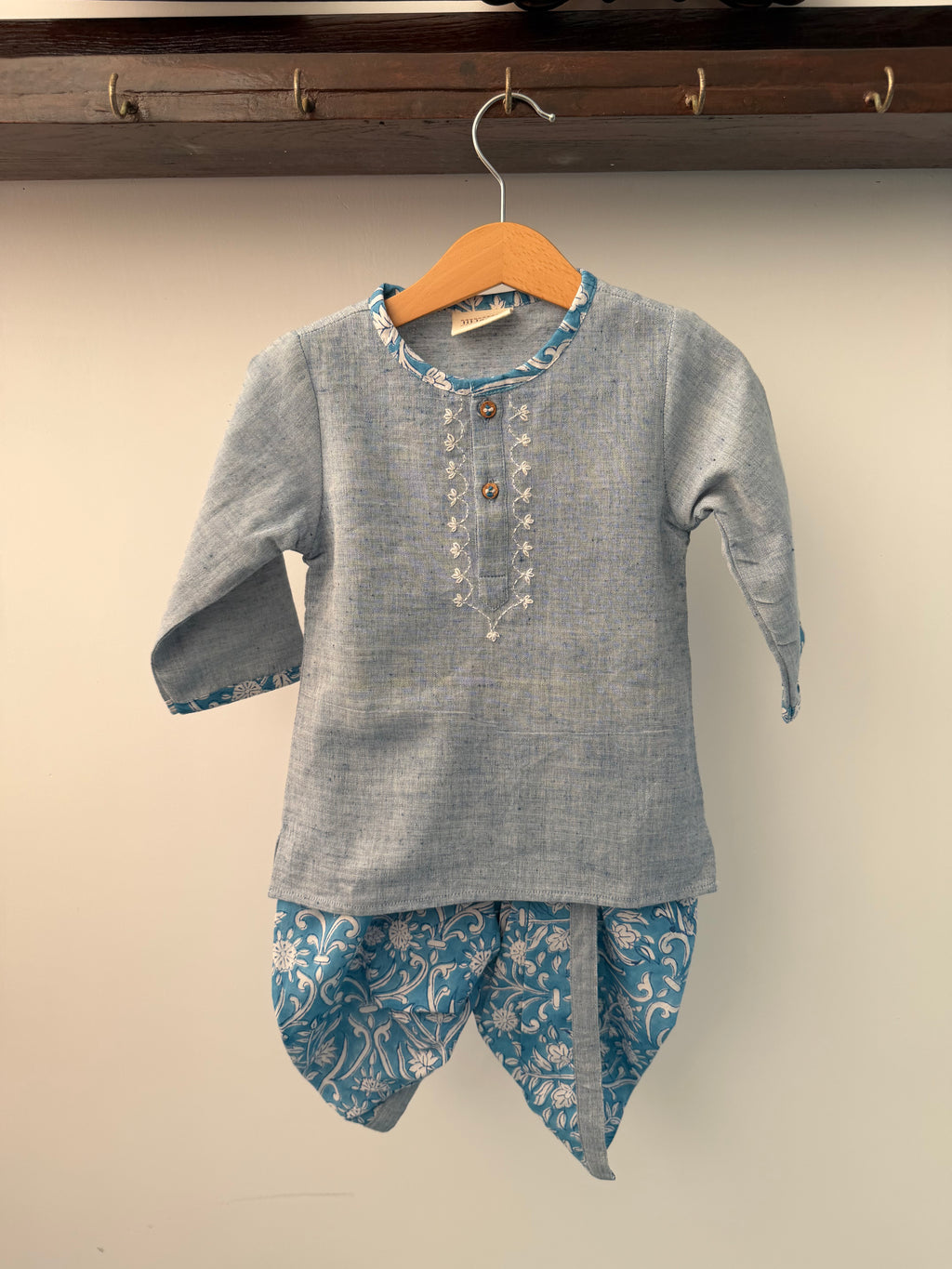 Blue embroidered shirt with floral patterns on a beige background