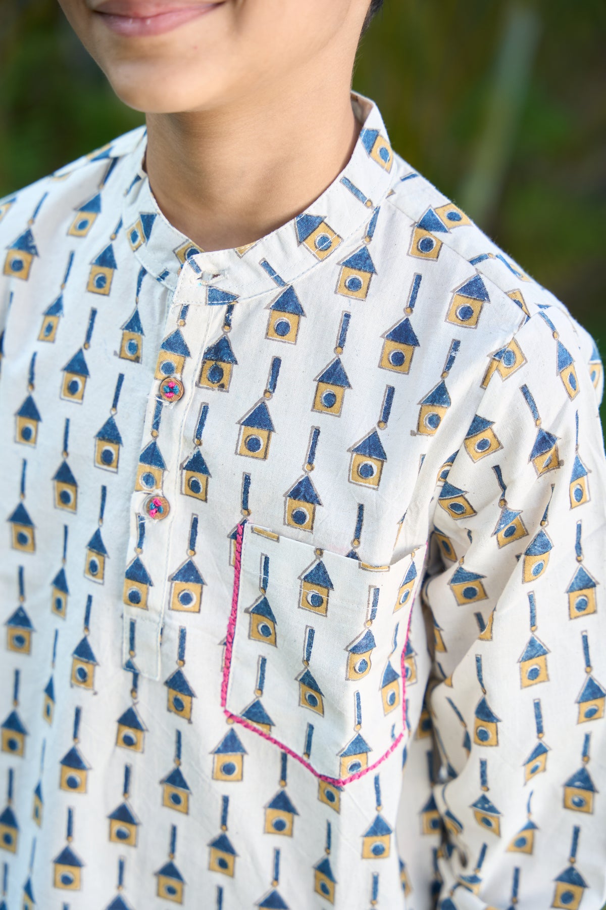 Close-up of a person wearing a white shirt with blue and yellow geometric pattern.