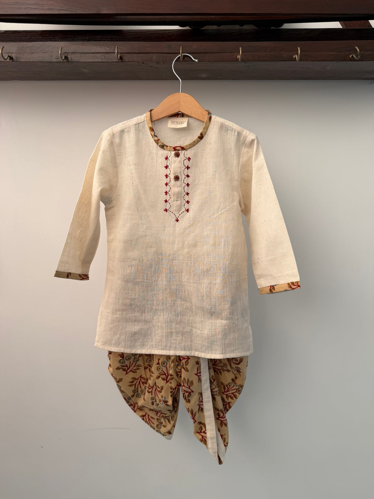 Traditional embroidered shirt on a hanger against a gray background