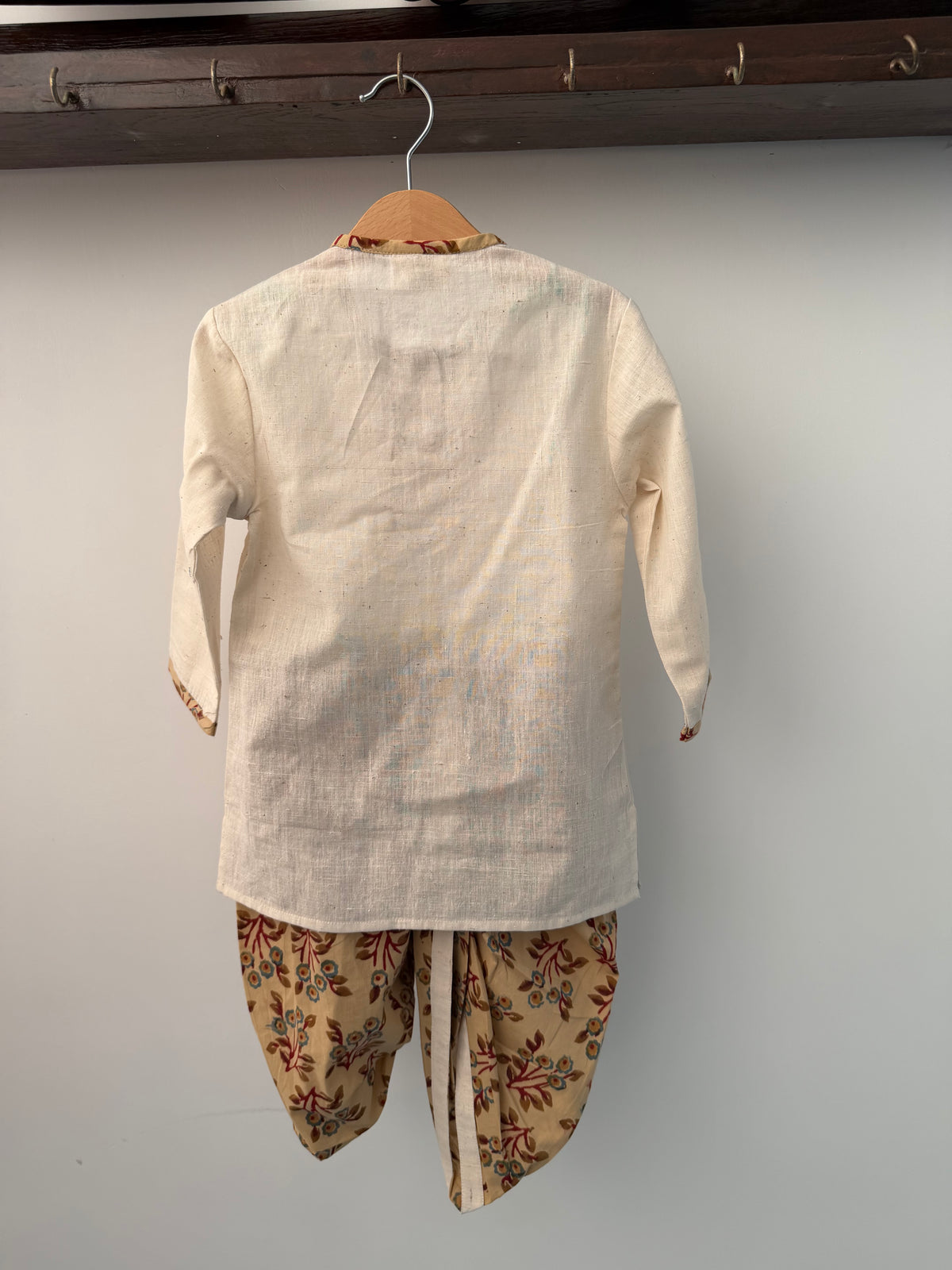 Mannequin wearing a beige shirt with floral sleeves against a plain background
