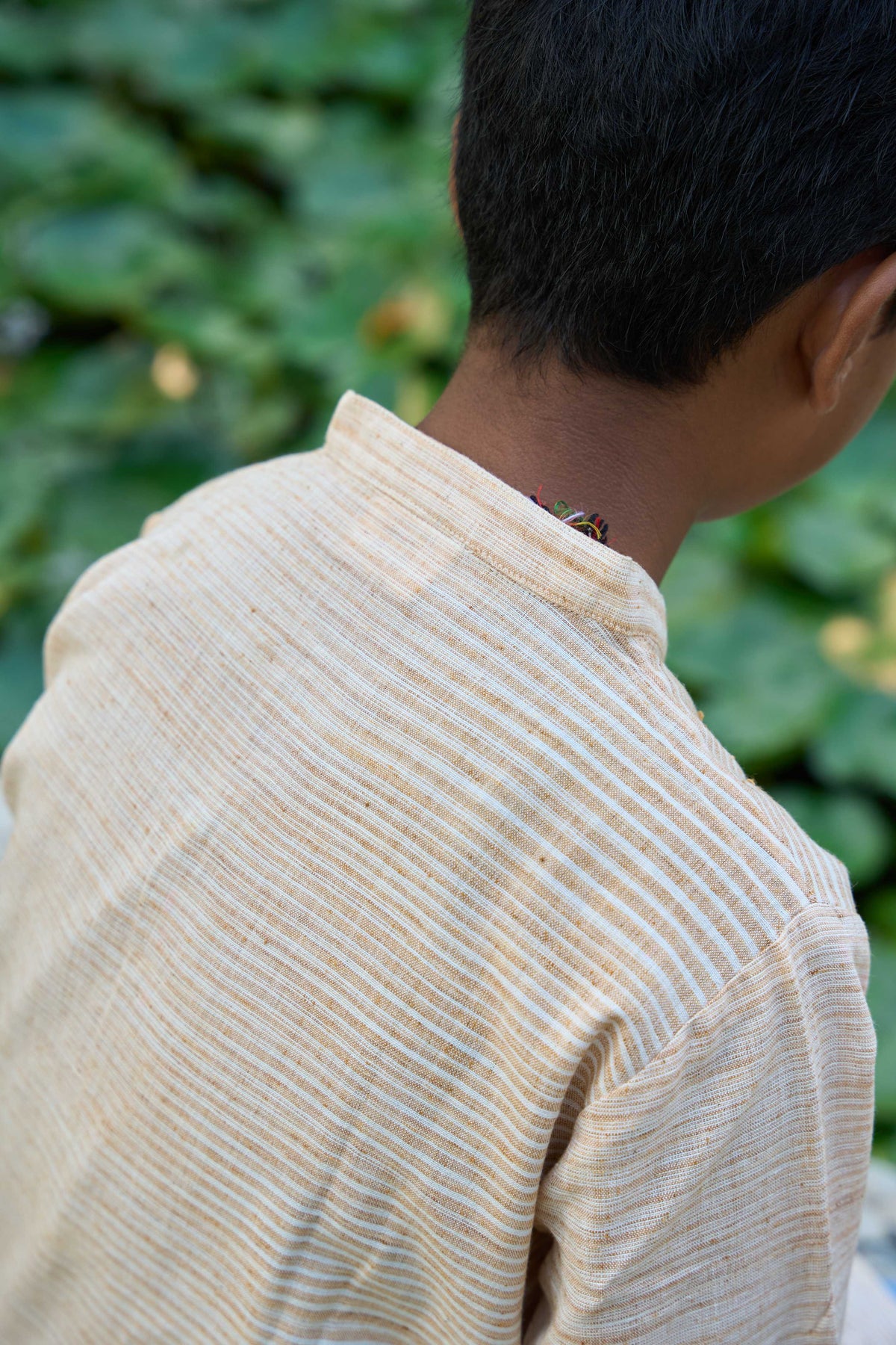 Person wearing a beige ribbed sweater with a blurred green background
