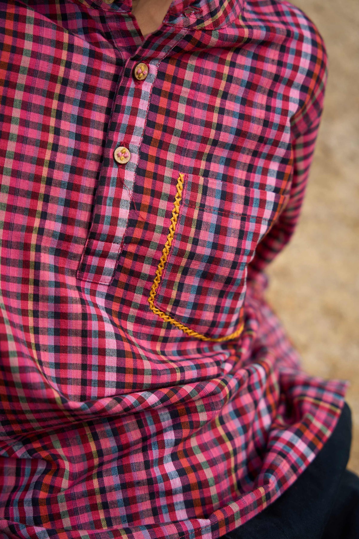 Red and black plaid shirt with a gold chain detail on a blurred background