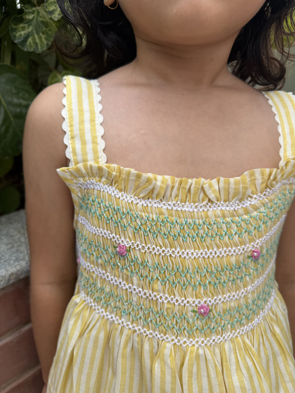 Yellow and white striped dress with smocked bodice worn by a child.