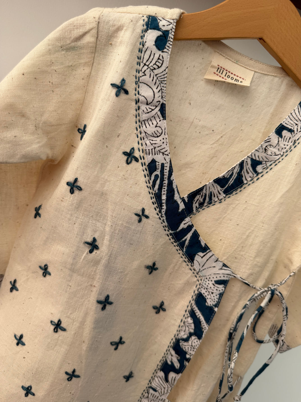 Close-up of a beige garment with blue floral patterns on a hanger.