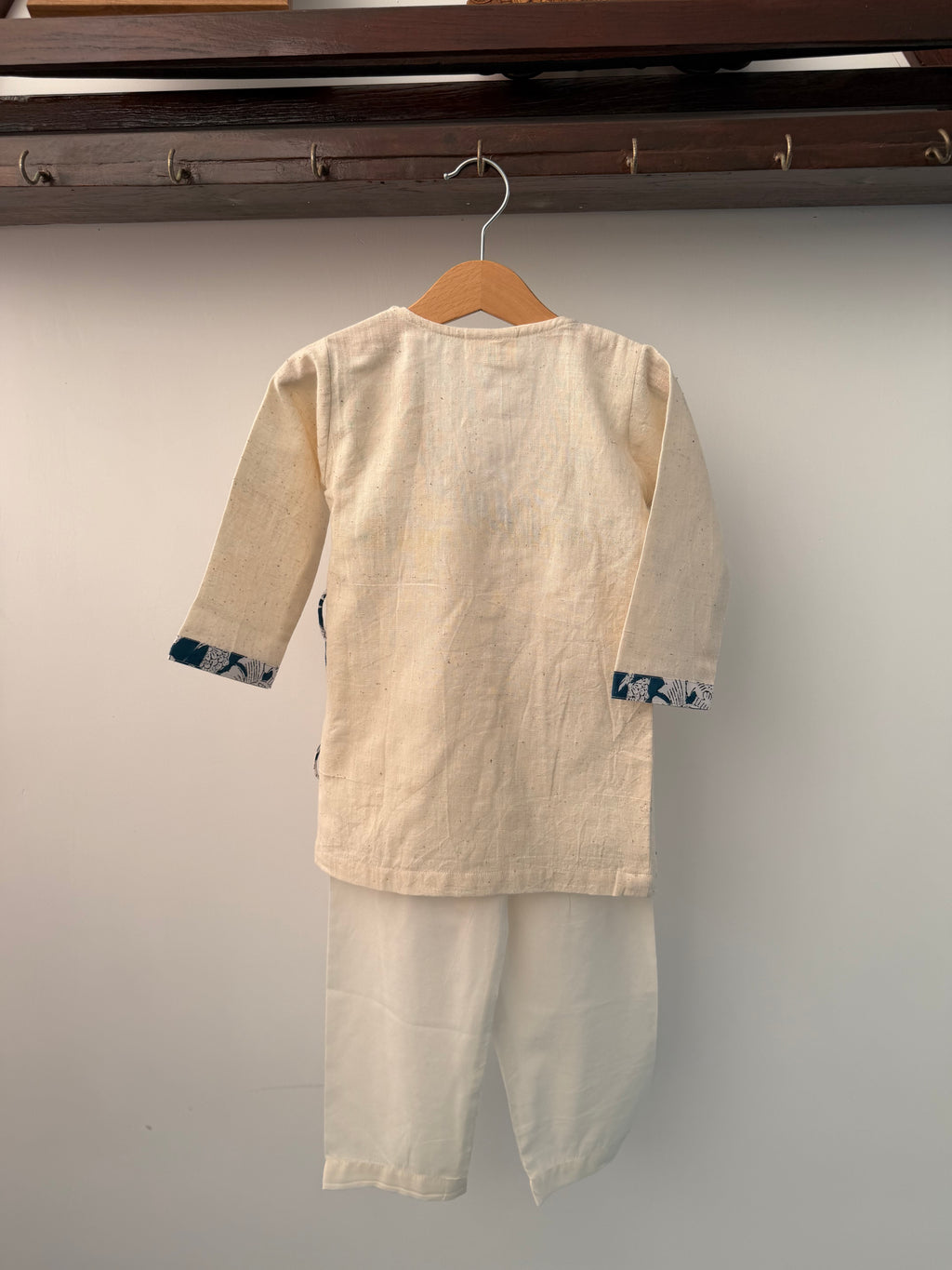Beige shirt on a hanger against a plain background