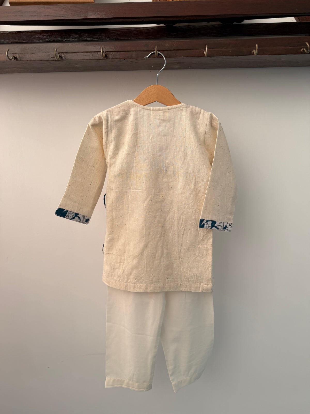 Beige shirt on a hanger against a plain background