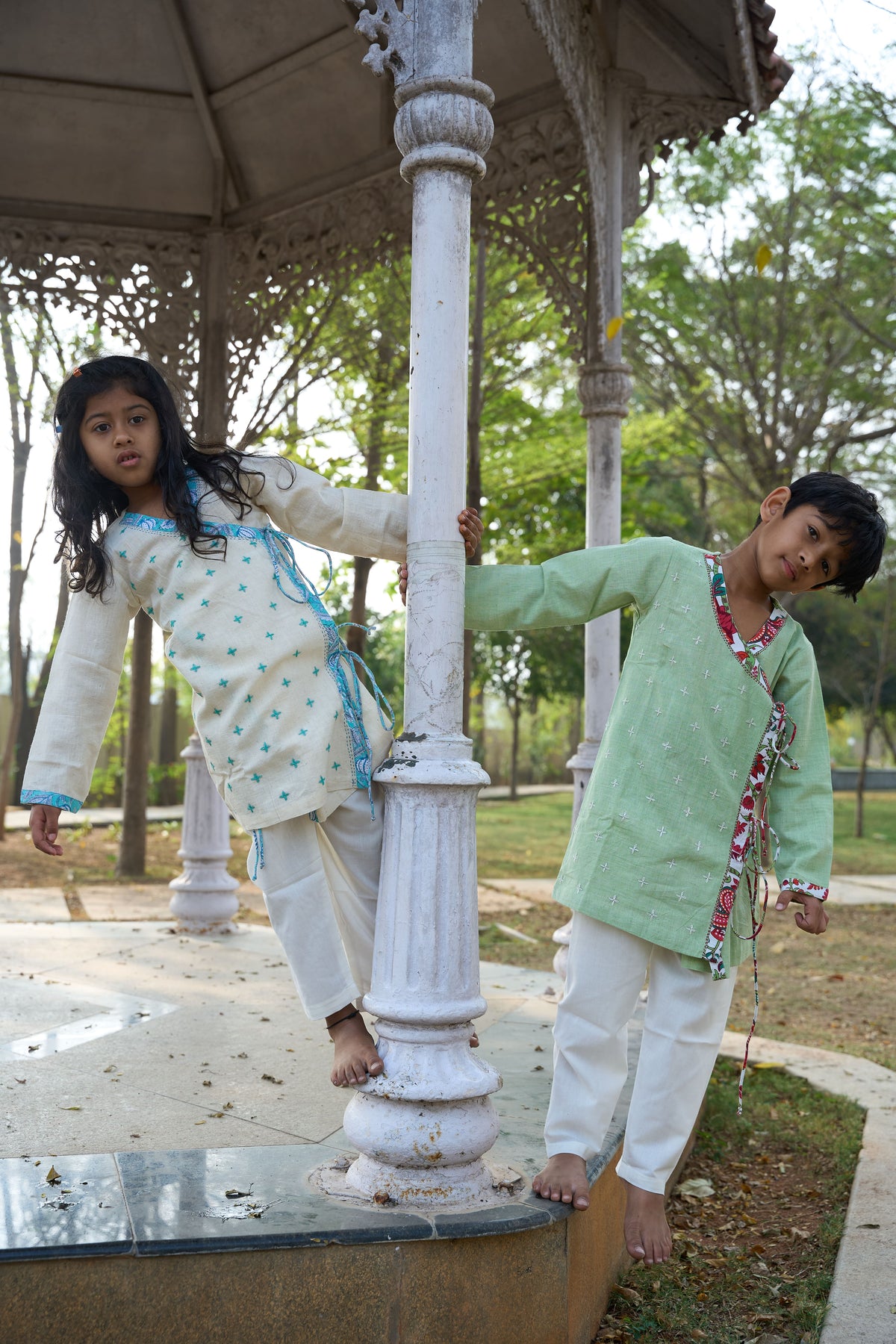 Two children posing near a gazebo in a park setting