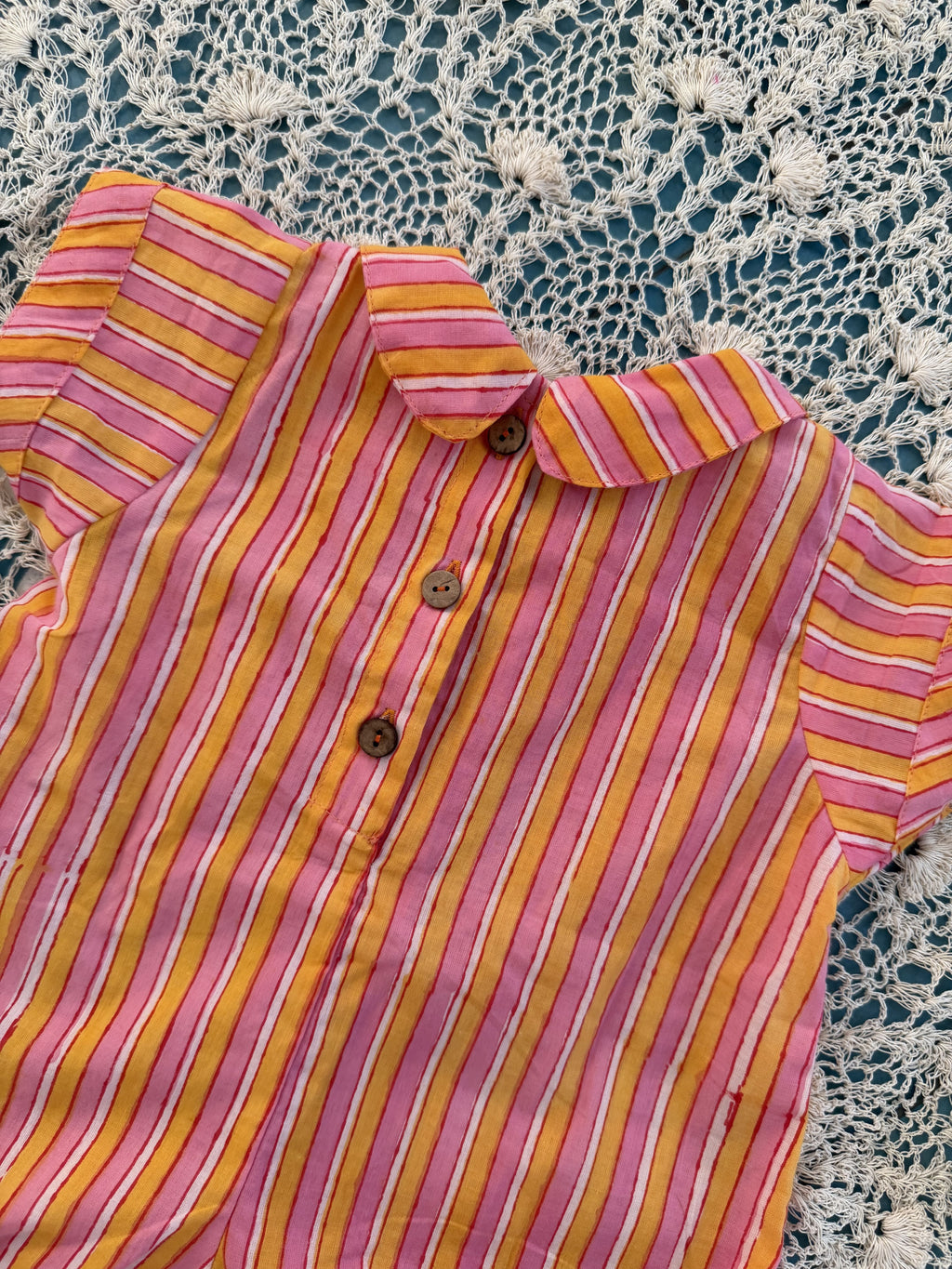 Pink and yellow striped shirt on a lace tablecloth