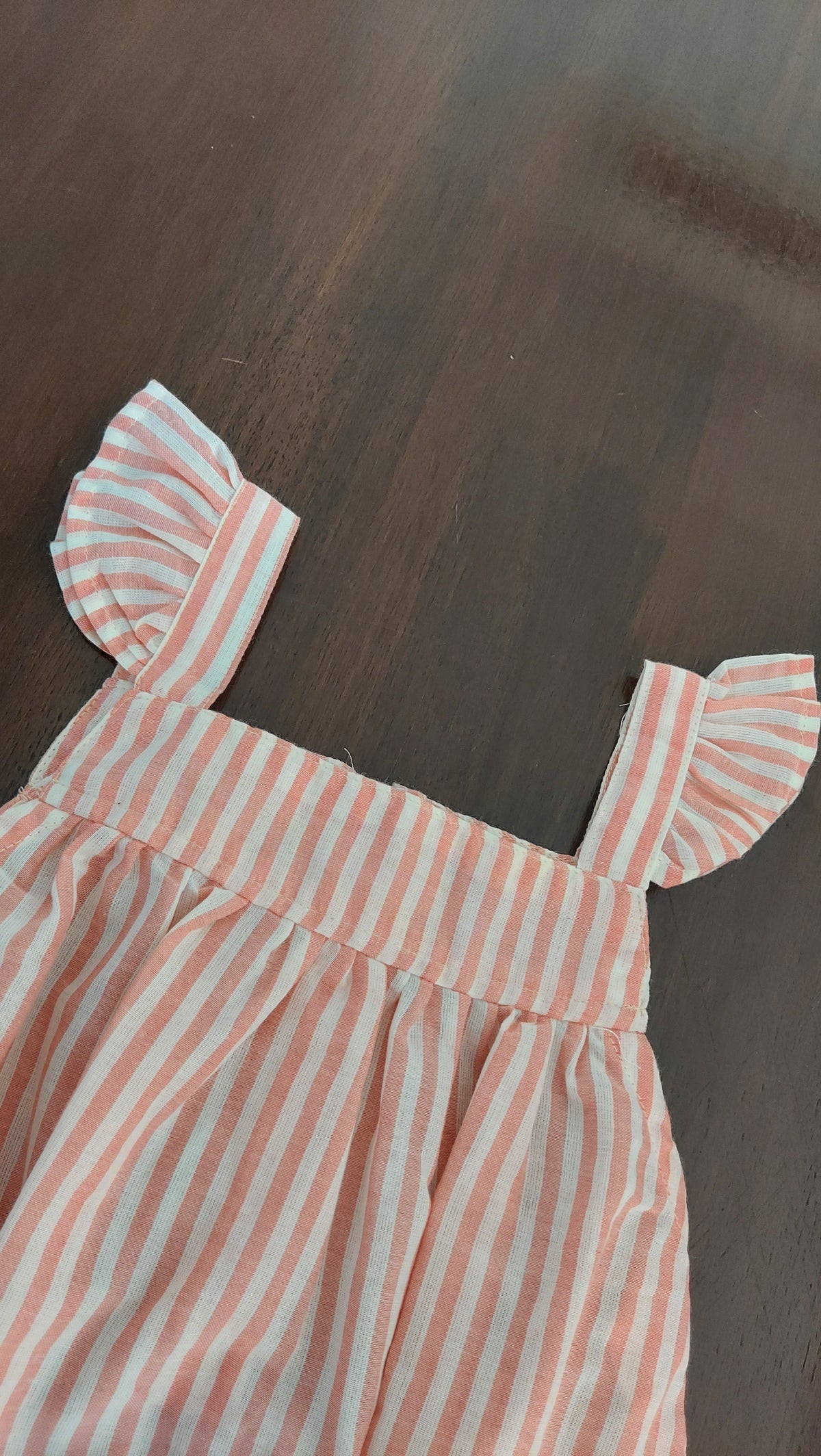 Striped romper with ruffled sleeves on a wooden surface
