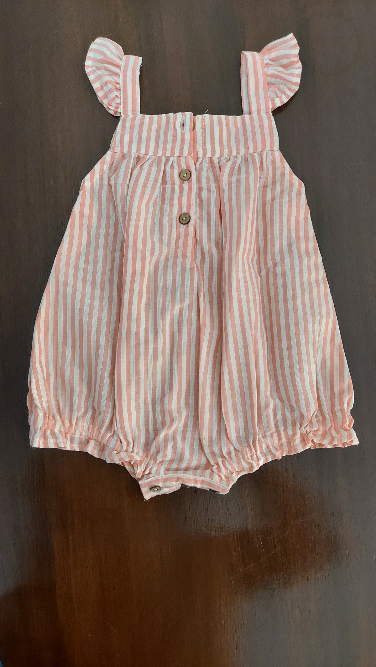 Pink and white striped dress with bow sleeves on a dark surface