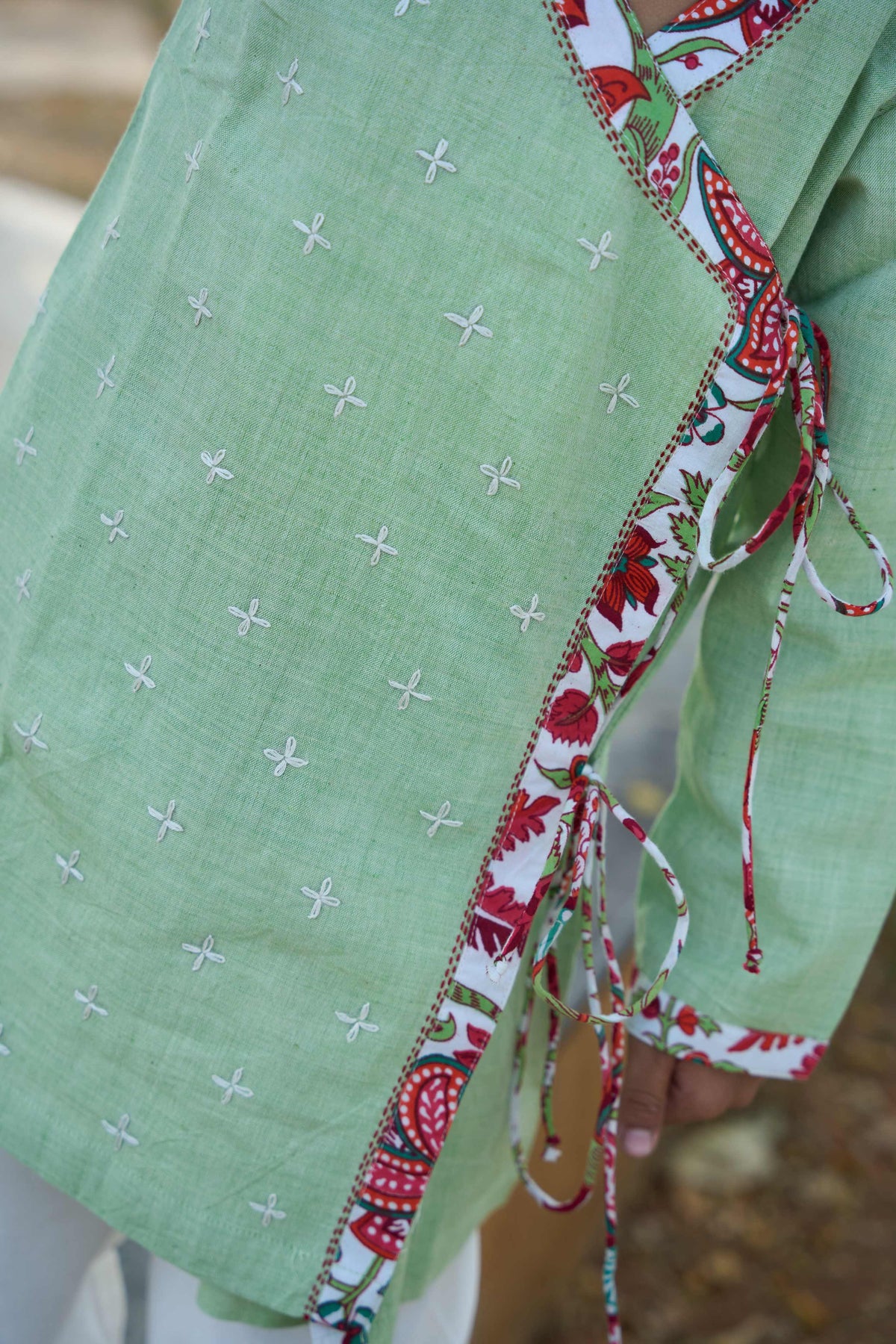 Green fabric with white cross pattern and colorful ribbon border.