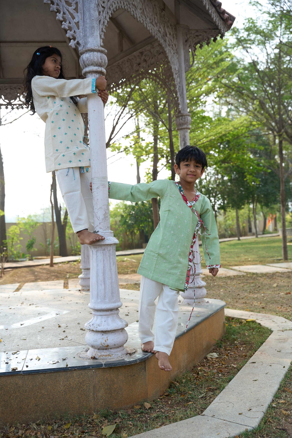 Two children playing on a decorative stone structure in a park.