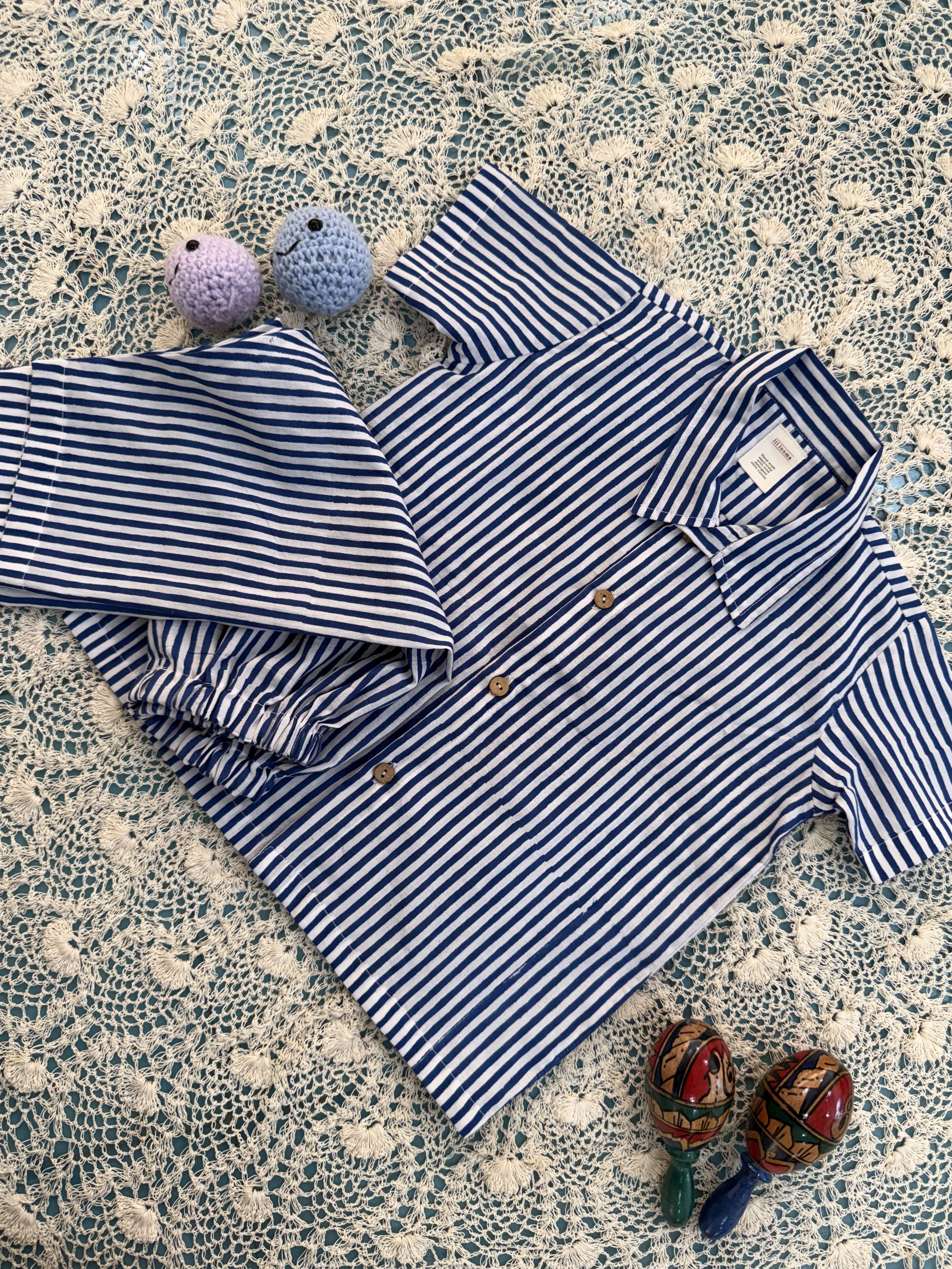 Blue and white striped shirt with matching shorts on a textured surface