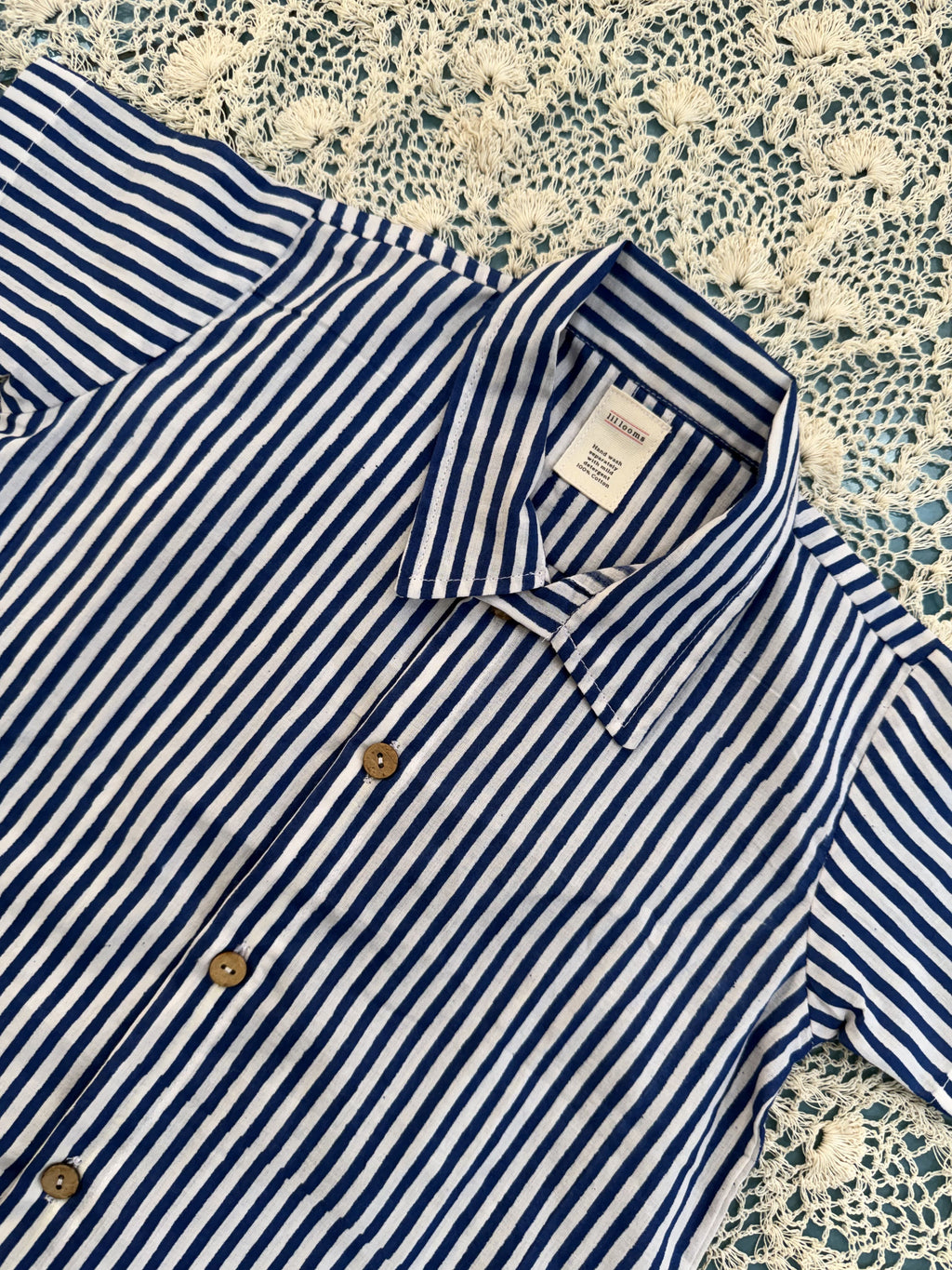 Blue and white striped shirt with a tag on a textured surface