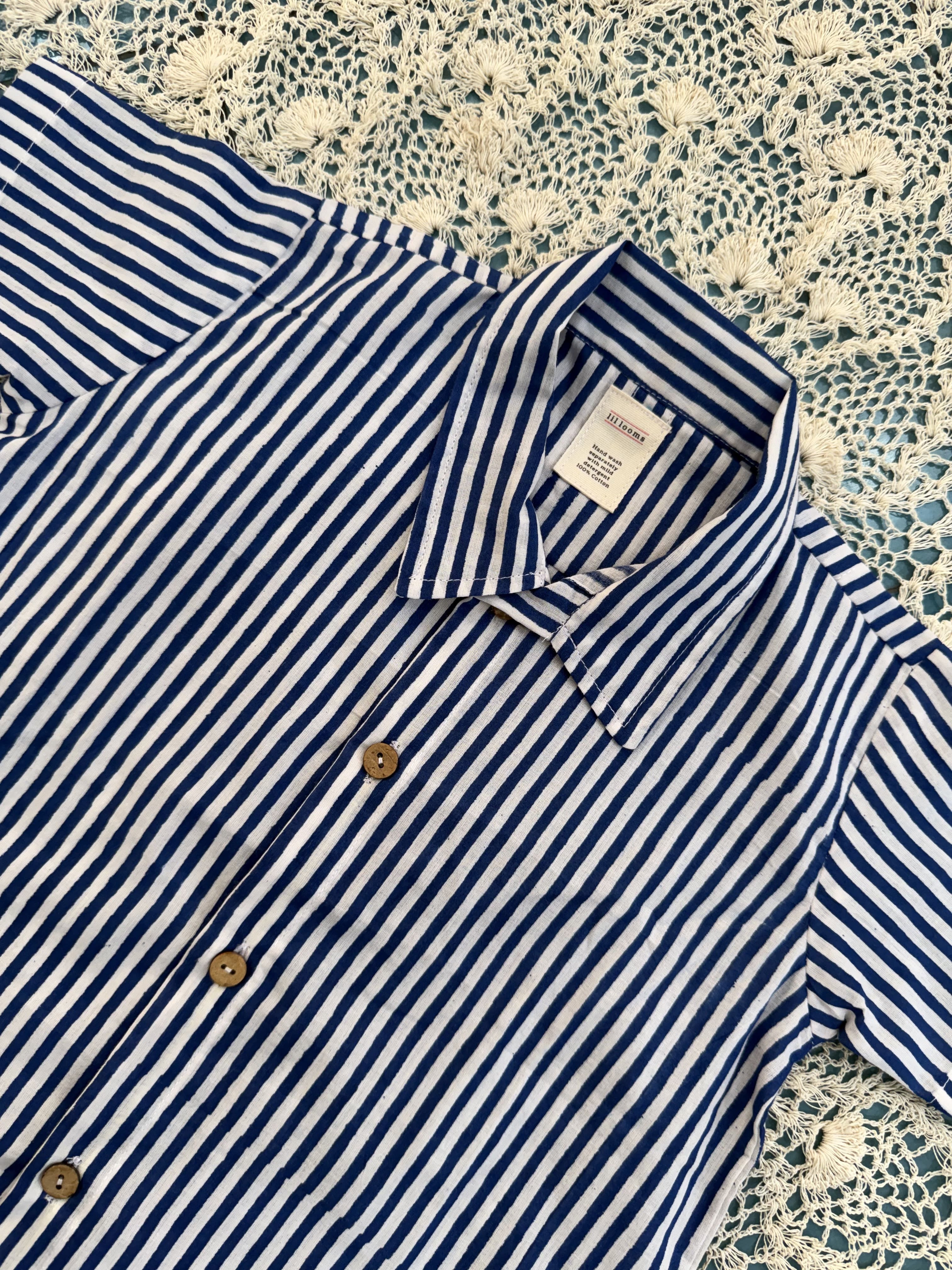 Blue and white striped shirt with a tag on a textured surface