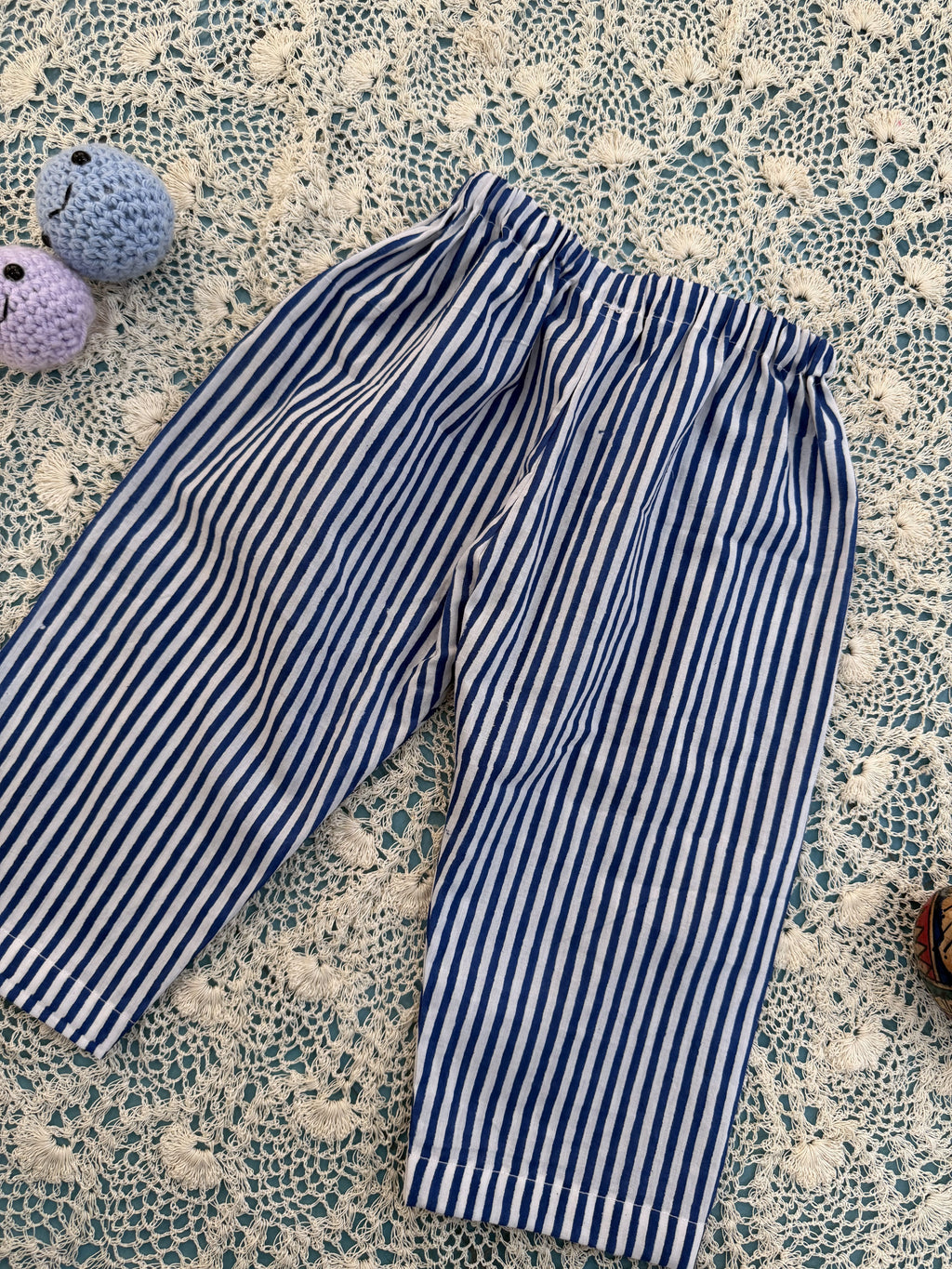 Blue and white striped pants on a textured surface with small plush toys.