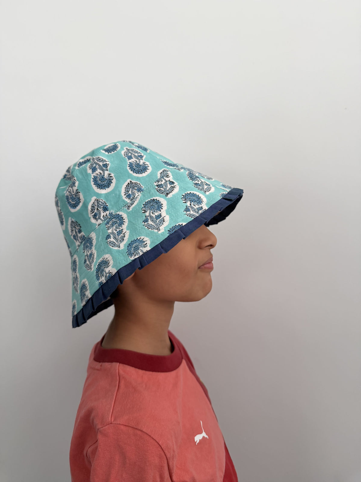 Person wearing a blue patterned headscarf against a plain background