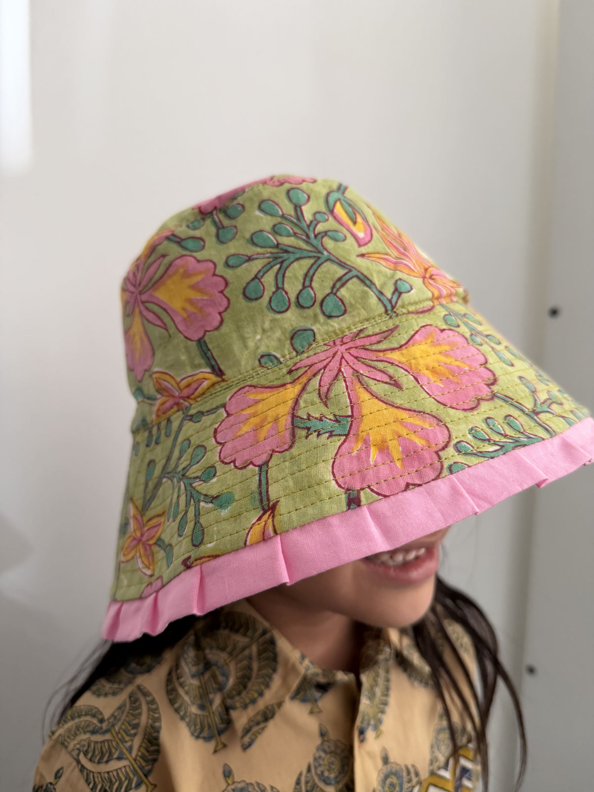 Person wearing a floral-patterned headscarf with pink trim on a white background
