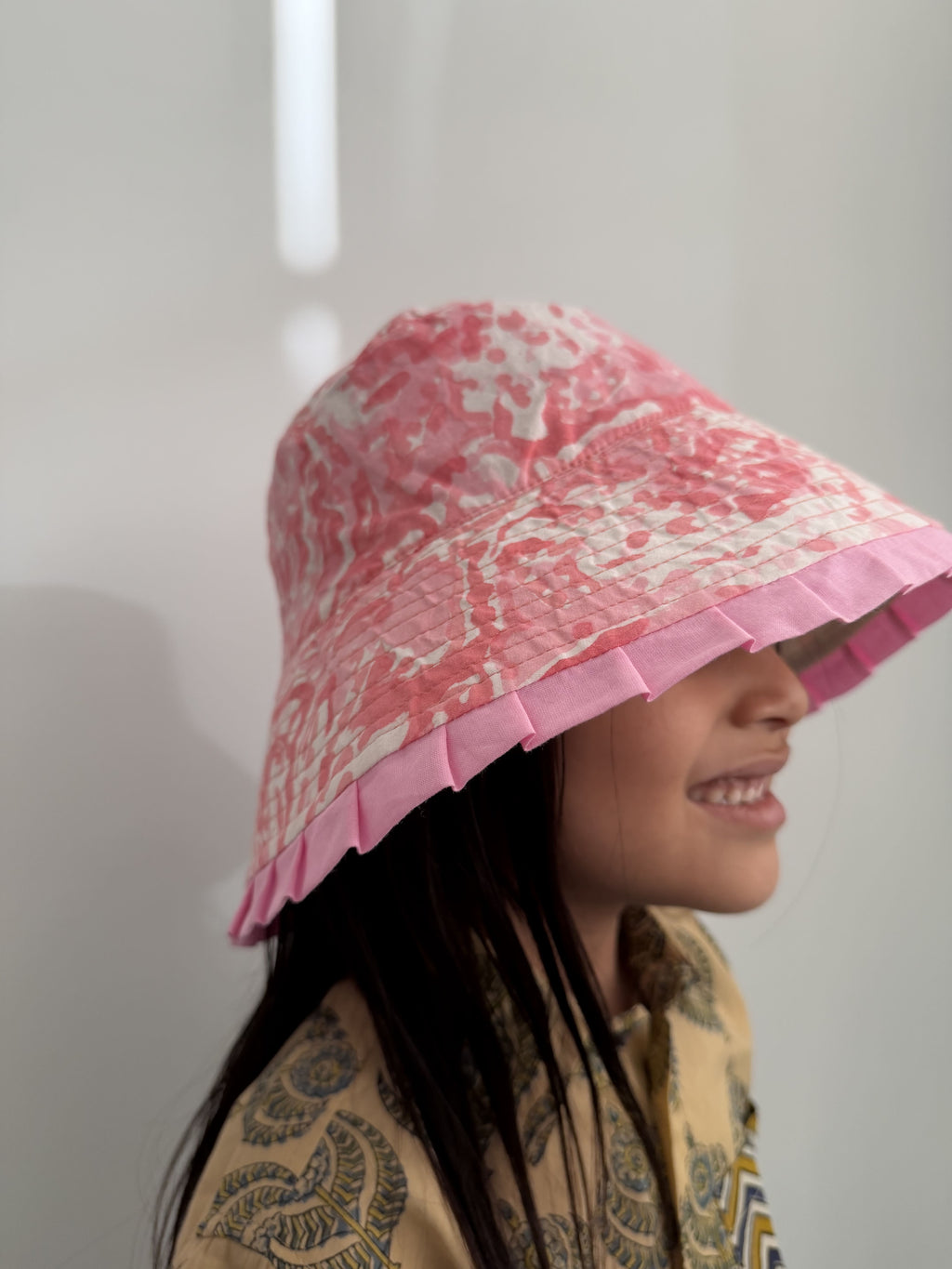 Person wearing a pink patterned hat against a plain background